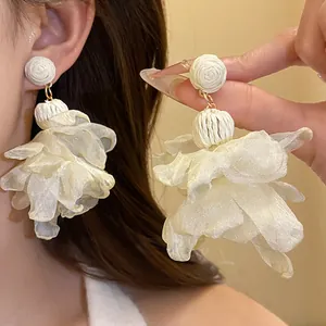 Dettaglio macro di orecchini a fiore in chiffon crema con base in raffia e aghi in acciaio
