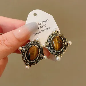 Close-up of retro palace style earrings featuring elliptical tiger eye stone and small pearls