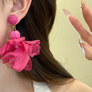 Primo piano di orecchini a fiore in rafia rosa e chiffon con perla