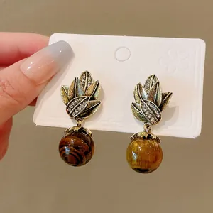 Retro palace style leaf stud earrings with vintage tiger eye stone beads on white card.