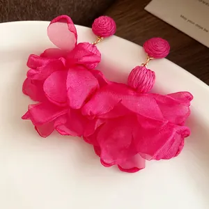 Vista dettagliata di orecchini a fiore in chiffon fucsia con perline di rafia rosa.