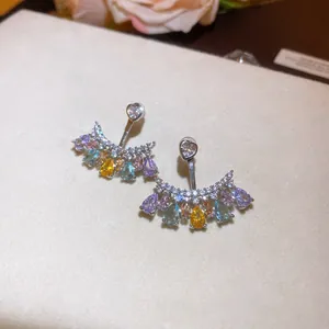 Dettaglio di orecchini vintage con zirconi colorati a goccia e perni a forma di cuore.