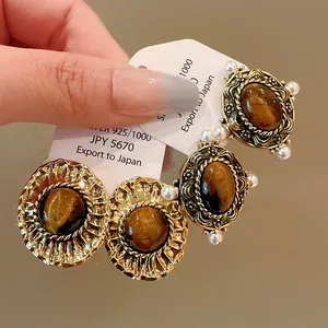 Detailed macro view of vintage tiger eye stone earrings with pearls and gold finish.