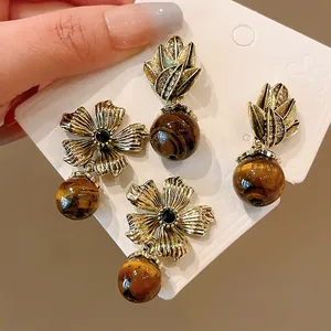 Close-up of vintage gold earrings with tiger eye stone beads and floral designs