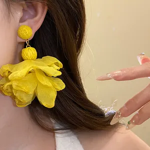 Primo piano di orecchini pendenti in rafia e chiffon giallo vibrante su una modella asiatica