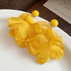 Dettaglio ravvicinato orecchini a fiore in chiffon giallo con perni in rafia intrecciata