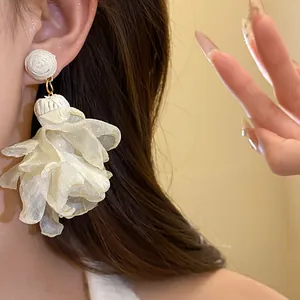 Primo piano di orecchini a pendente a fiore in rafia e chiffon con dettagli in perla.