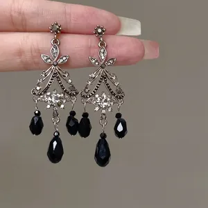 Detailed view of vintage silver flower earrings with sparkling zircon and black bead dangles.