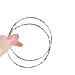 Large silver hoop earrings with a wavy textured finish for a minimalist chic style.