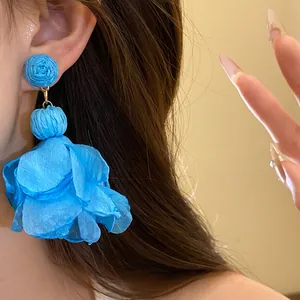 Dettaglio di un orecchino a fiore in chiffon blu con perno avvolto in rafia indossato