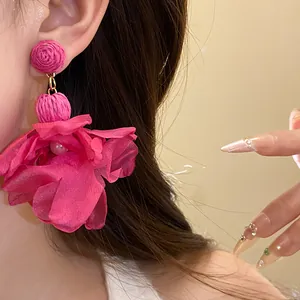 Dettaglio orecchini a fiore in chiffon magenta con perno in rafia e perla centrale
