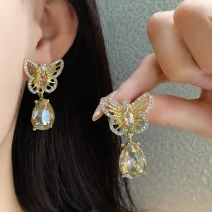 Macro detail of vintage hollow butterfly dangle earrings with teardrop champagne crystal