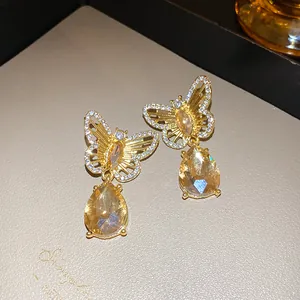 Close-up of vintage hollow butterfly drop earrings with yellow teardrop crystals.