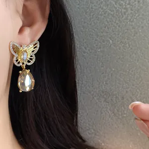 Close-up of vintage gold hollow butterfly earrings with crystal teardrop pendant