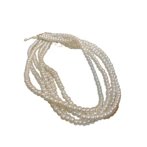 Elegant multi-strand white pearl necklace with gold-toned clasp on white background