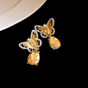 Detailed view of gold hollow butterfly earrings with elegant amber teardrop pendants.