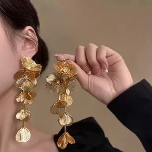 Close-up of golden layered flower dangling earrings with sparkling zircon centers