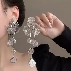 Detailed view of silver flower tassel earrings with zircons on model