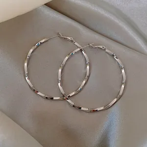 Detailed view of silver twisted large hoop earrings on elegant satin