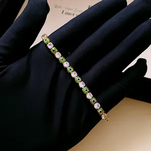 Close-up view of gold-plated tennis bracelet with square zircons and green evil eye beads