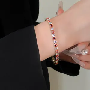 Close-up of a gold-plated tennis bracelet with red evil eye beads and sparkling cubic zirconia.