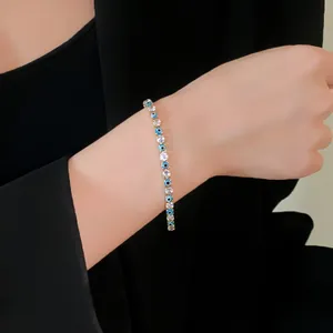 Close-up of a delicate evil eye and cubic zirconia bracelet worn on a woman's wrist