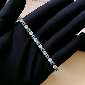Detailed macro view of evil eye and sparkling zirconia stones on a gold-tone bracelet.