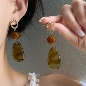 Close-up of vintage amber-toned drop earrings featuring golden hammered hoops and resin beads.