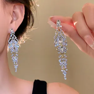 Detail view of elegant long dangling zircon floral earrings for party wear and luxury look.