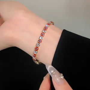 Detail shot of a sparkling red evil eye and clear cubic zirconia bracelet on a wrist