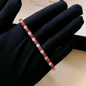 Close-up of elegant gold-tone bracelet with red evil eye beads and square zircons