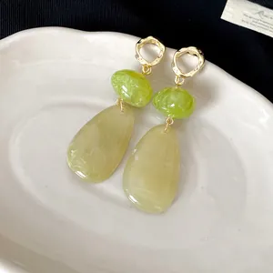 Detail of vintage-style drop earrings featuring green and yellow marbled resin pendants.