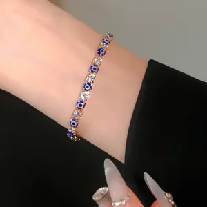 Close-up detail of elegant gold evil eye and sparkling round zircon bracelet on wrist