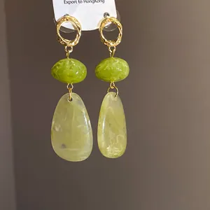 Close-up detail of retro teardrop earrings featuring vibrant green and pale yellow stones