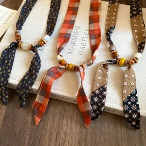 Detailed view of Bohemian fabric and bead necklaces with floral and plaid prints.