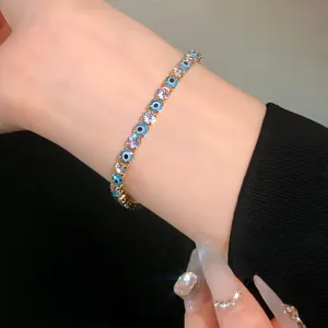 Detail shot of elegant gold evil eye and sparkling round zircon tennis bracelet on a wrist.