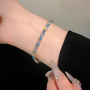 Close-up of gold-plated tennis bracelet with evil eye motifs and clear cubic zirconia