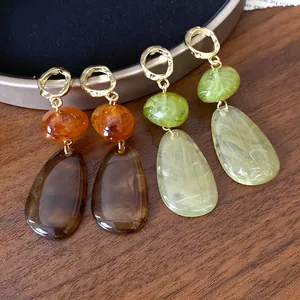 Close-up of retro teardrop earrings in amber and green color contrast resin