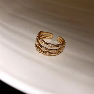 Détail macro d'une élégante bague dorée à trois couches en forme de bambou avec des zircons.