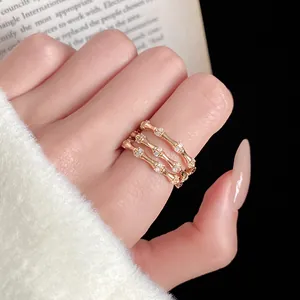 Gros plan de trois bagues en forme de bambou en or rose avec zircons sur une main