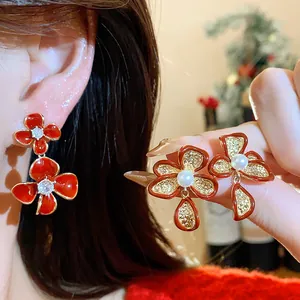 Detailed macro shot of elegant red enamel flower earrings with pearl and zircon accents