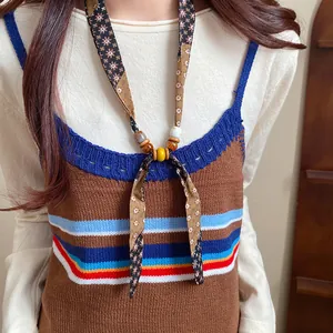 Close-up of a bohemian chiffon fabric necklace with wooden and ceramic beads on model