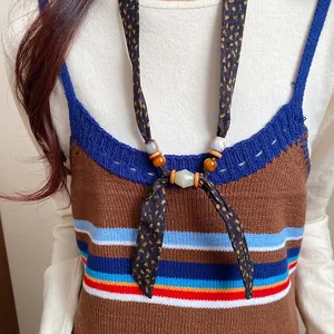 Detailed macro view of bohemian fabric necklace featuring wood and ceramic beads on model