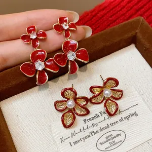 Detailed close-up of 18k gold plated red flower earrings with pearls and zirconia
