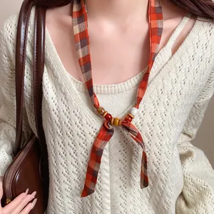 Close-up of a bohemian plaid chiffon necklace with wood and ceramic beads on a model