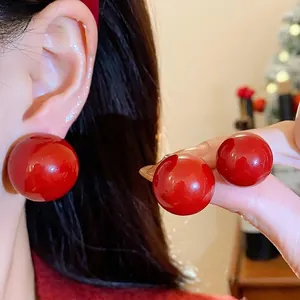 Elegante übergroße rote Perlenohrstecker mit glänzendem Finish an einem asiatischen Model.