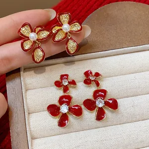 Close-up of elegant 18k gold plated flower earrings with red enamel and sparkling zircons