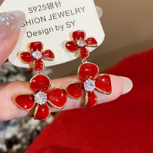Close-up detail of red flower drop earrings with clear zircon center and gold plating