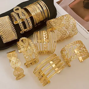 Detailed view of multiple gold-plated woven and geometric metal open cuff bracelets.