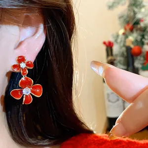 Detailed view of elegant red double flower stud earrings with zircon center worn on ear